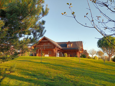 Magnificent log chalet set in 1 ha of wooded grounds. Balconies, terraces, parking, habitable on one level.